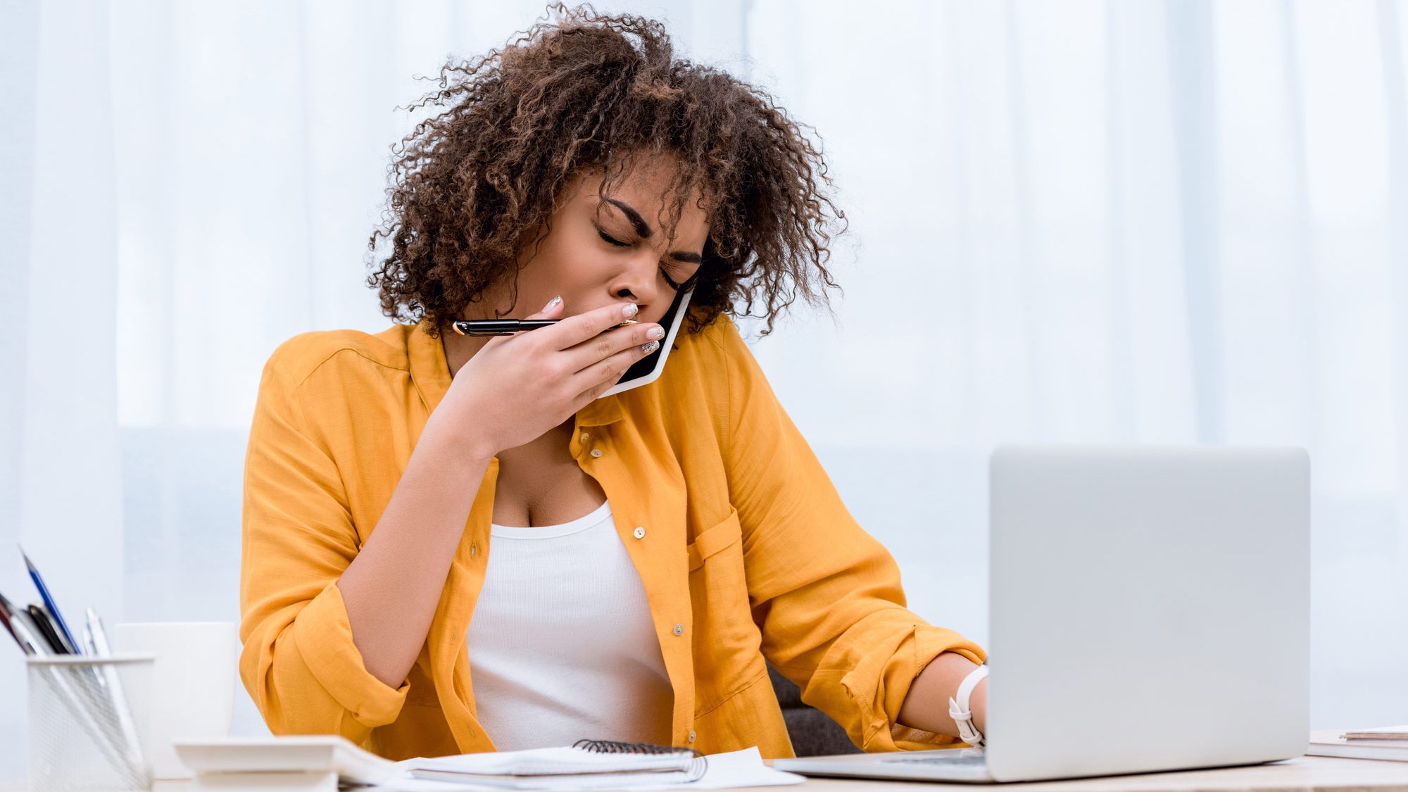 woman sitting at a desk yawning