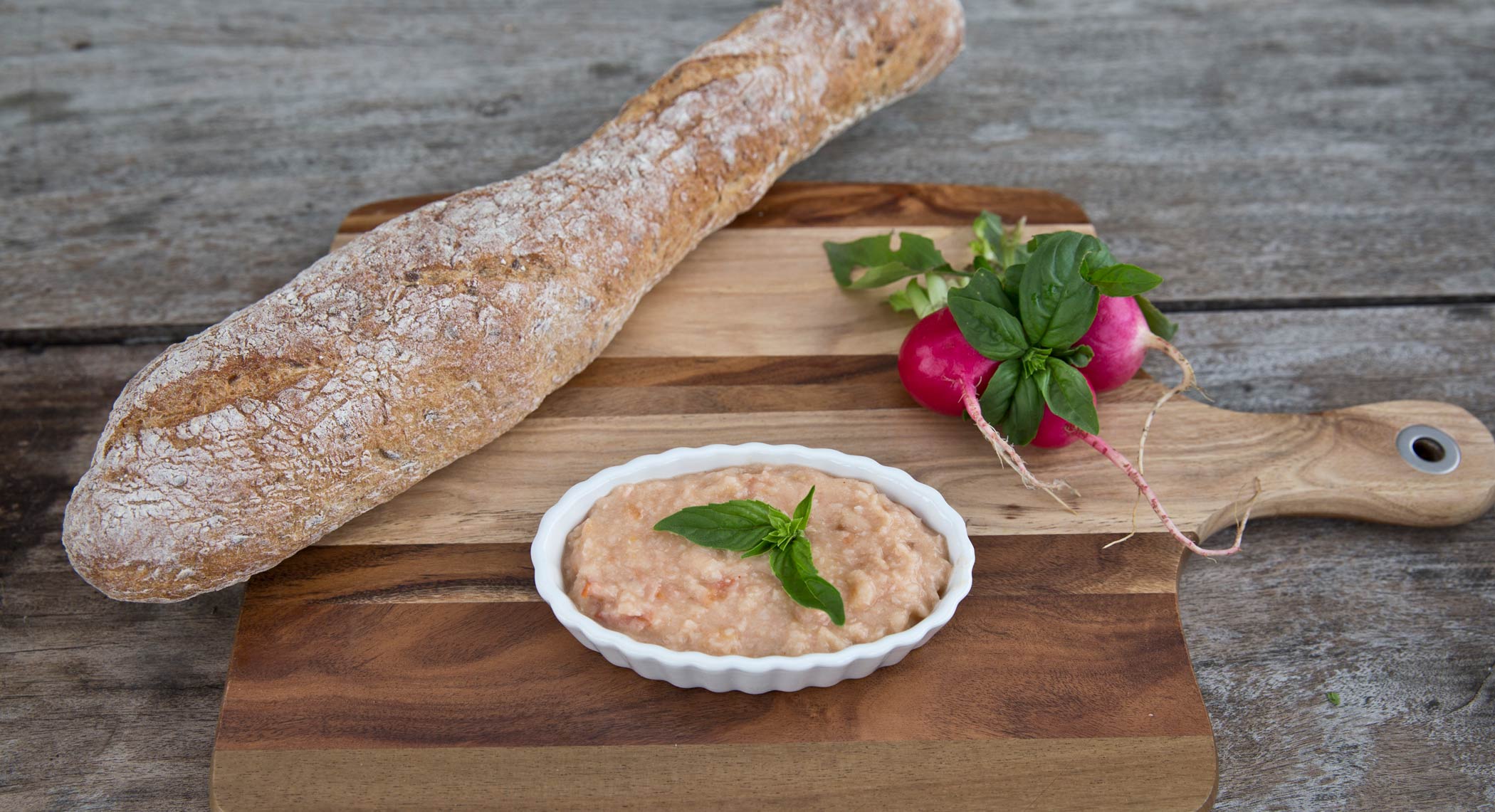 white bean spread in a small plate with rustic bread next to it