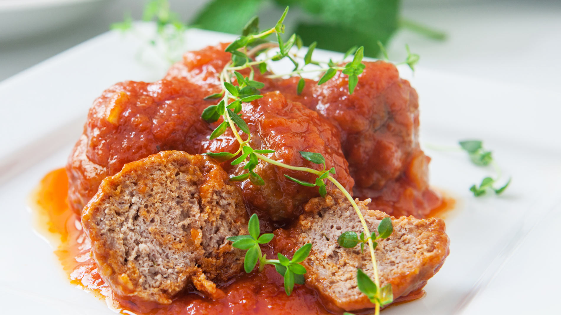 a plate of vegan meatballs coated with tomato sauce