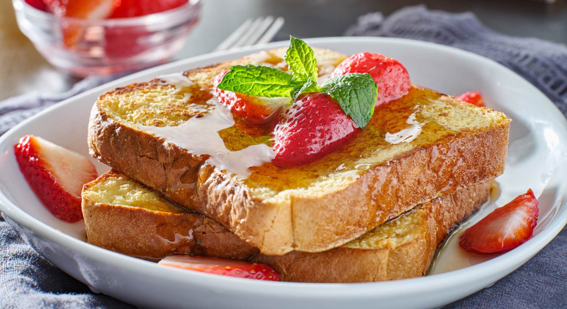 2 slices of french toast with maple syrup and fresh strawberries