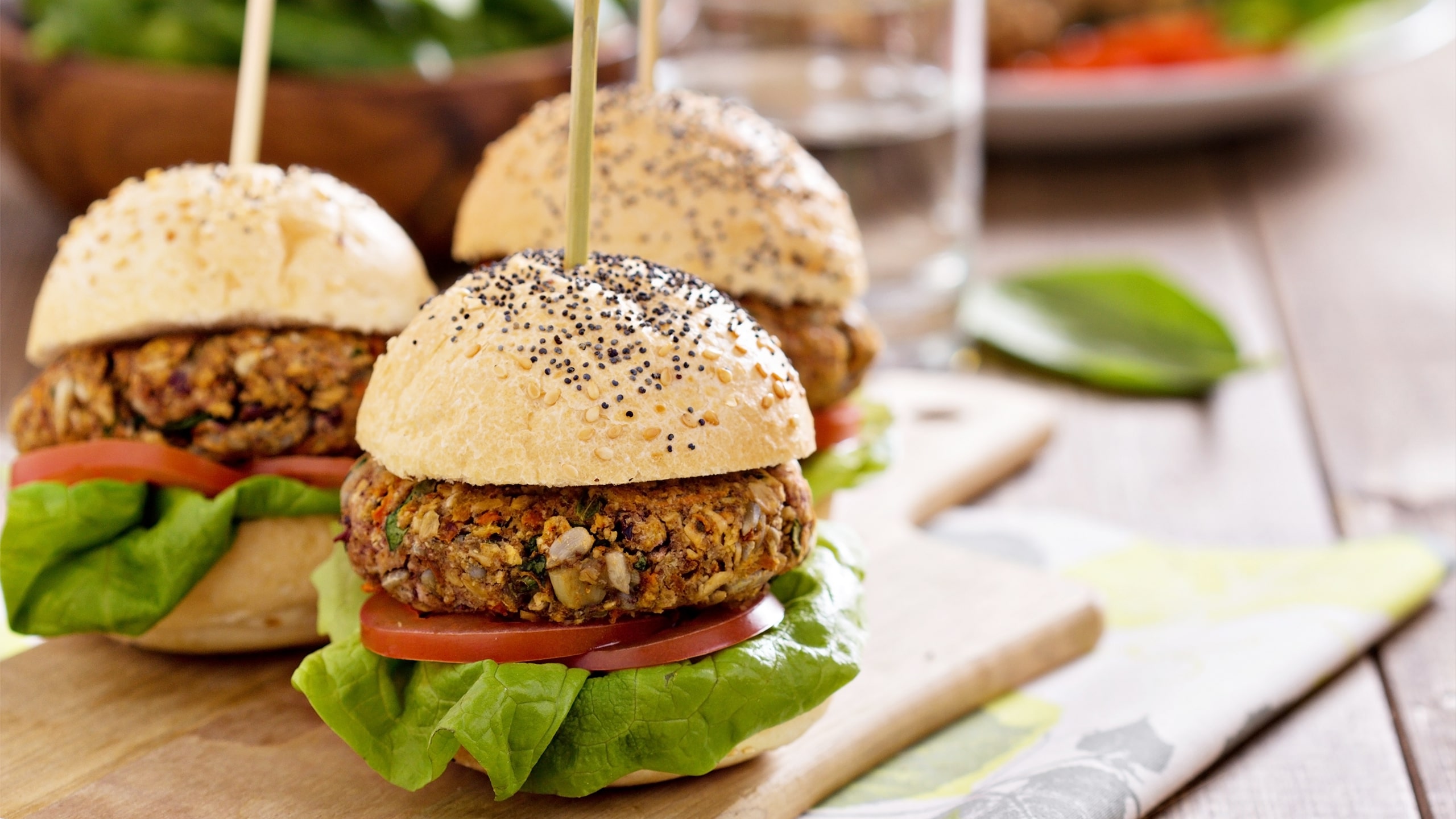 3 vegan homemade burgers in buns with vegetables