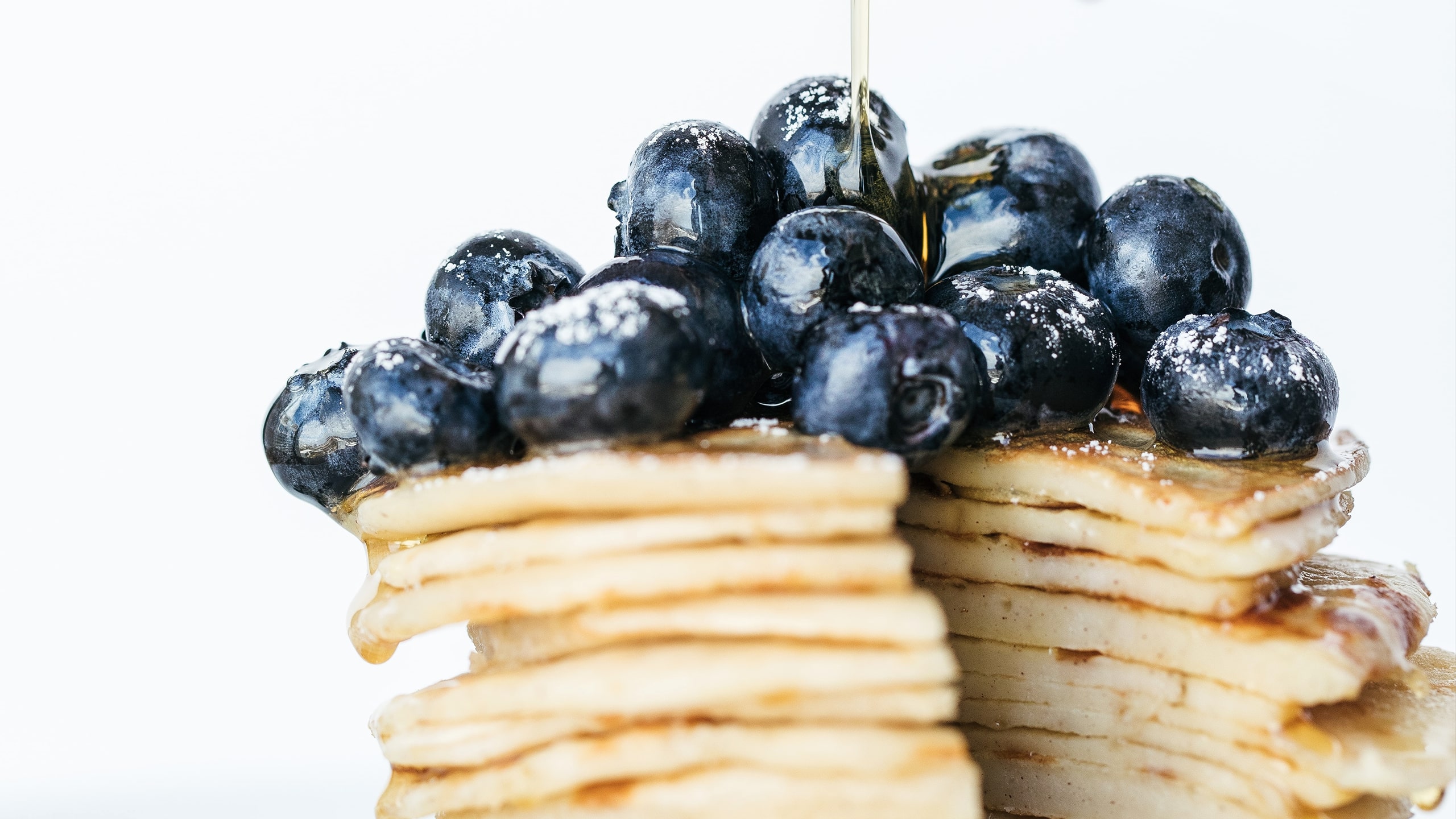 pile of pancakes with blueberries and drizzled vegan honey on top