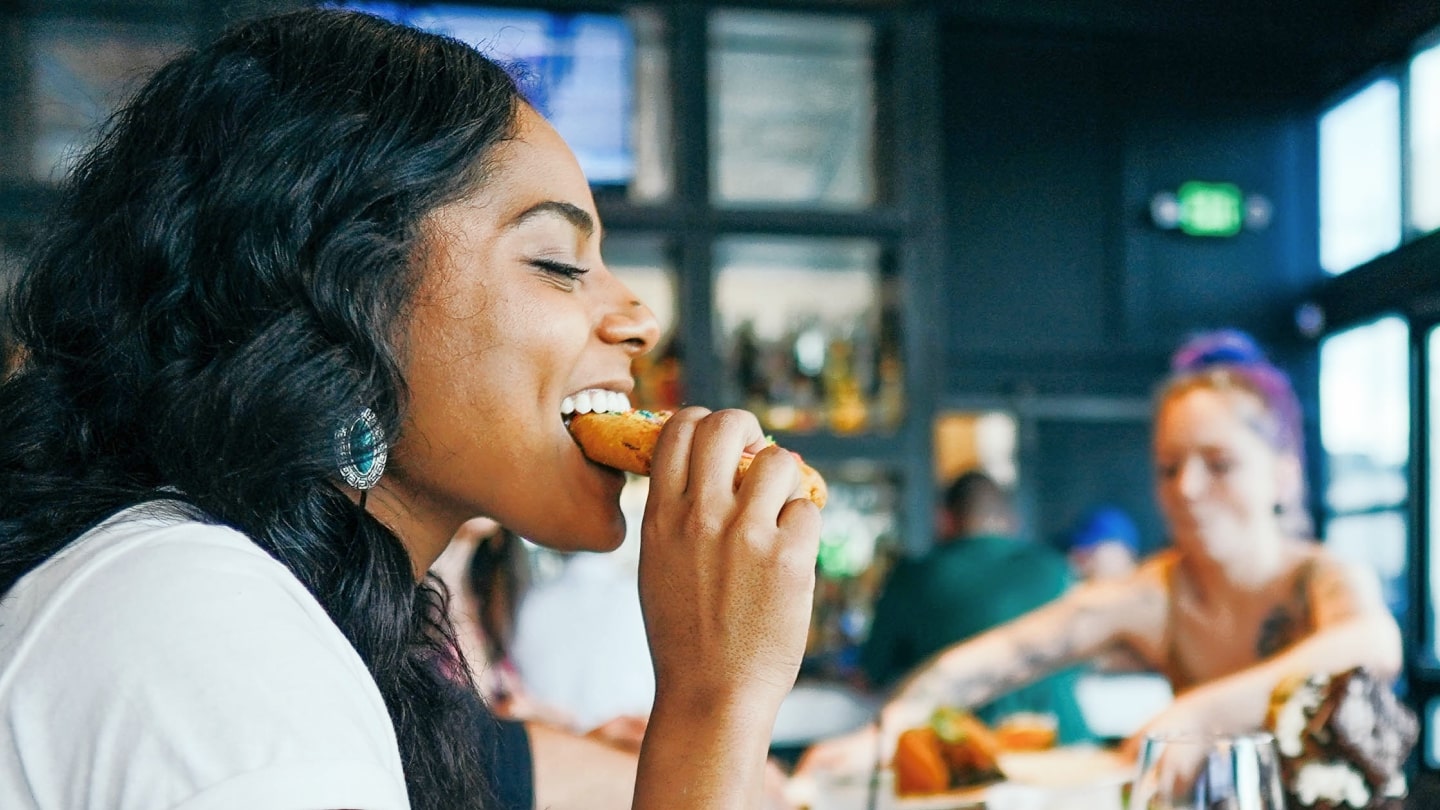 woman taking a bite in a vegan schnitzel