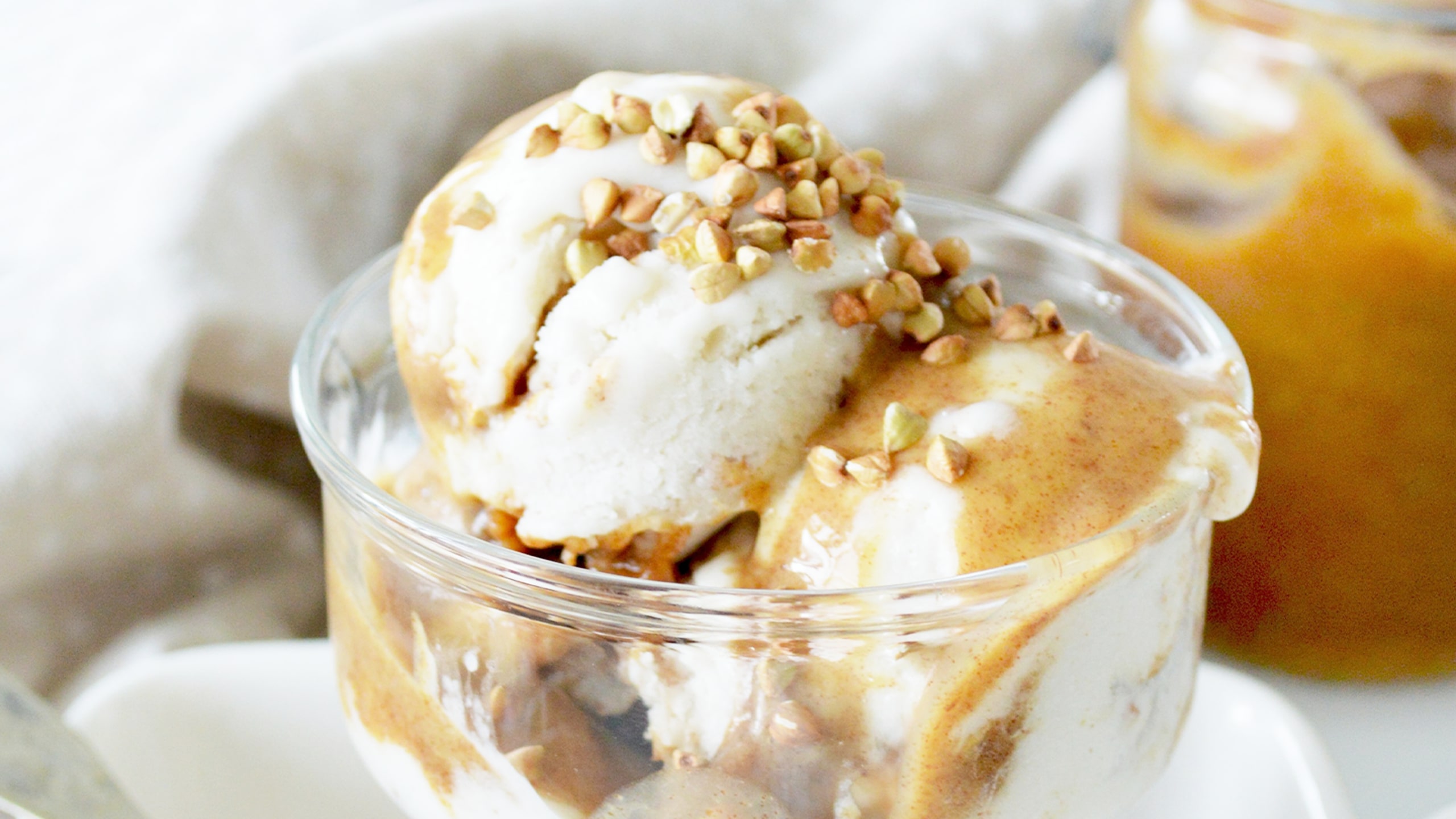 vegan vanilla ice cream in a cup with caramel sauce and chopped nuts