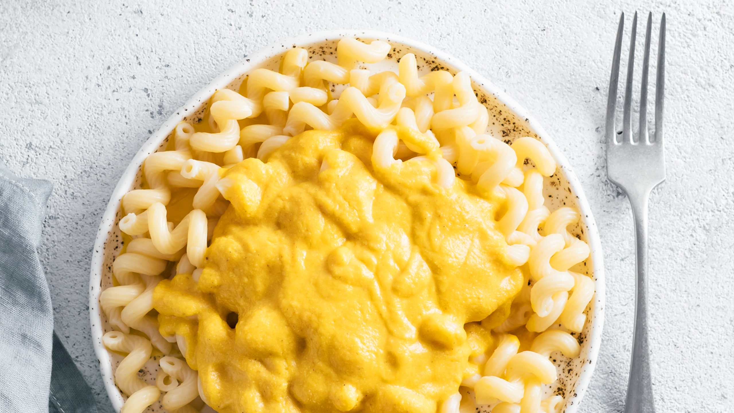 bowl full of cooked curly pasta with thick creamy cheesy sauce on top