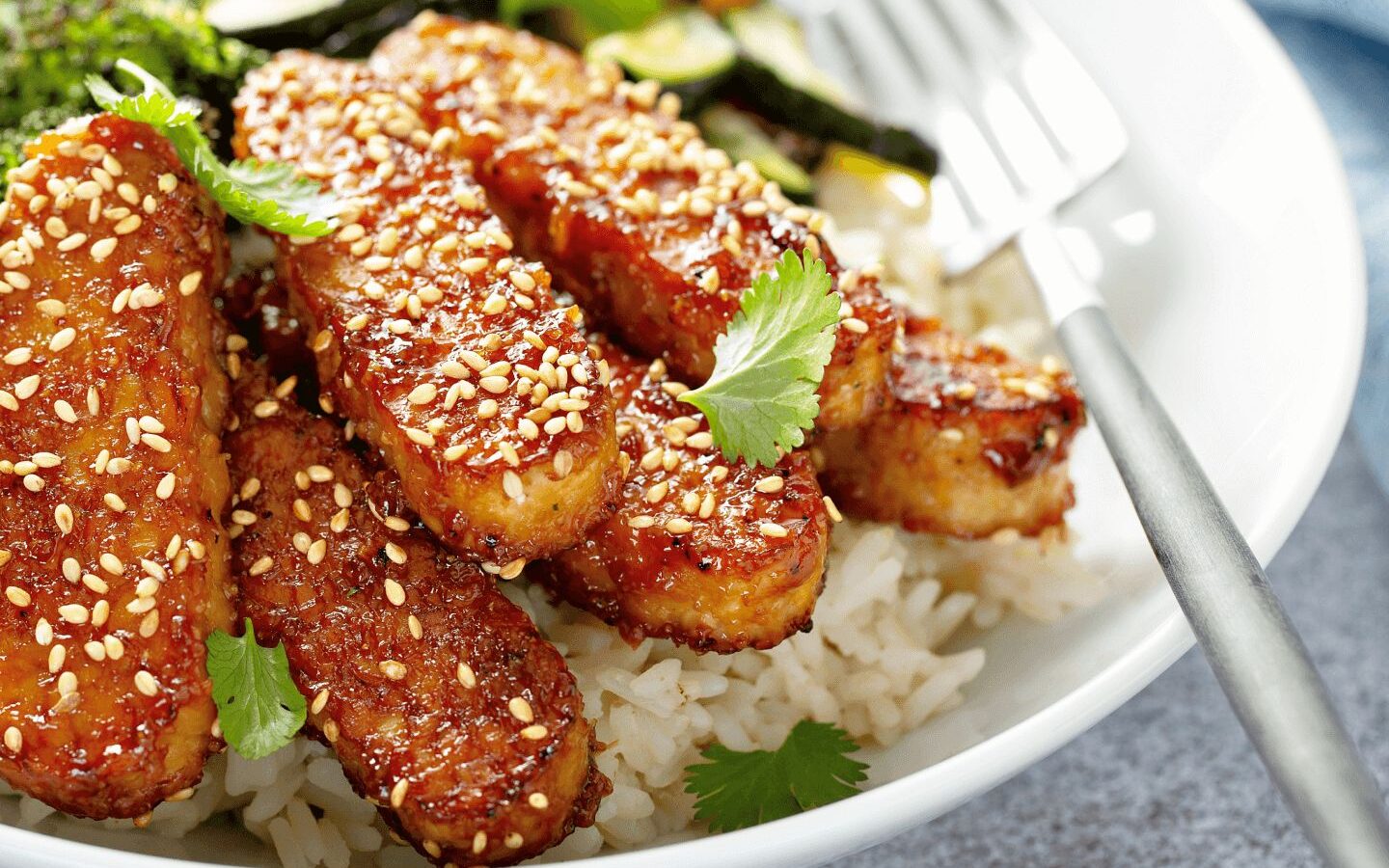 strips of tempeh coated with sesame on top of white rice