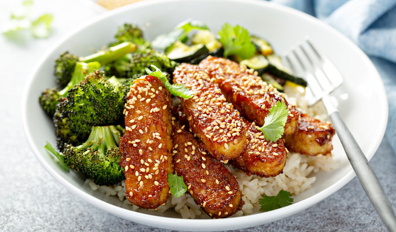 baked tempeh strips with sesame on top of rice and steamed broccoli