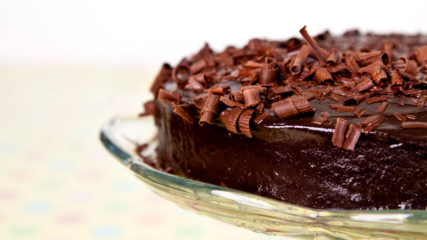 a round chocolate cake with frosting and chocolate flakes