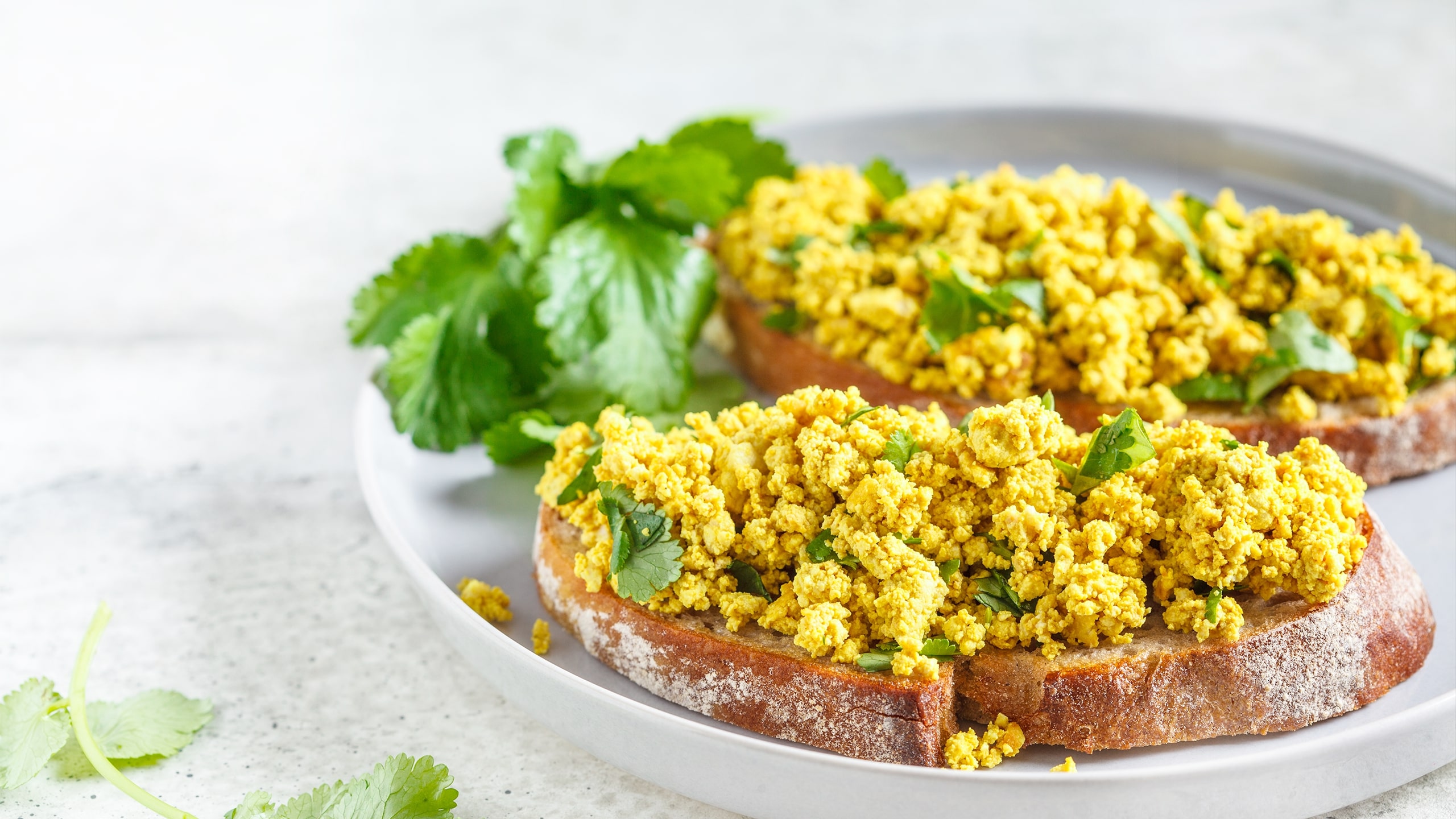 scrambled tofu on two slices of bread with parsley for garnish