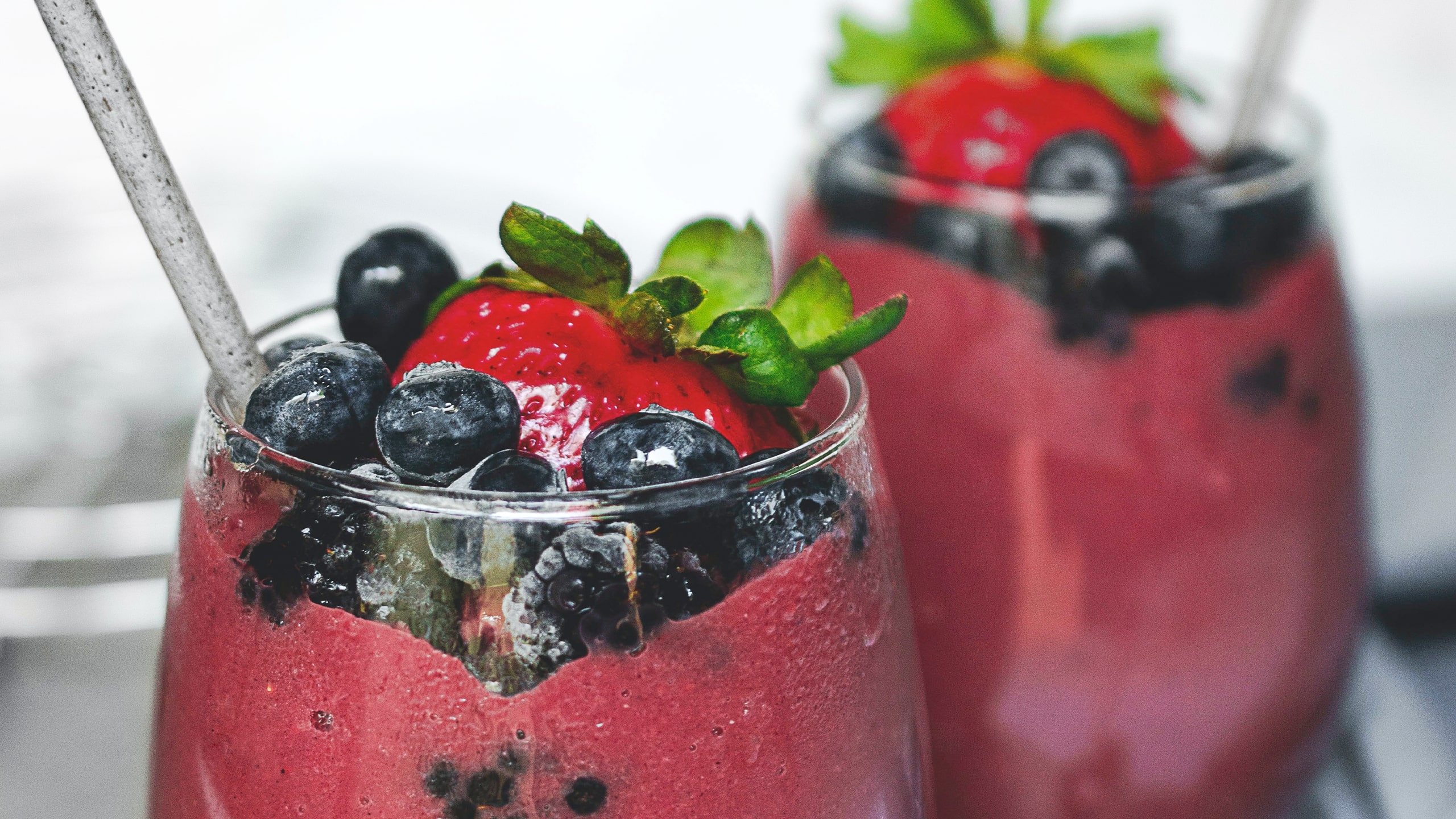 thick berry smoothie topped with fresh berries in a clear glass