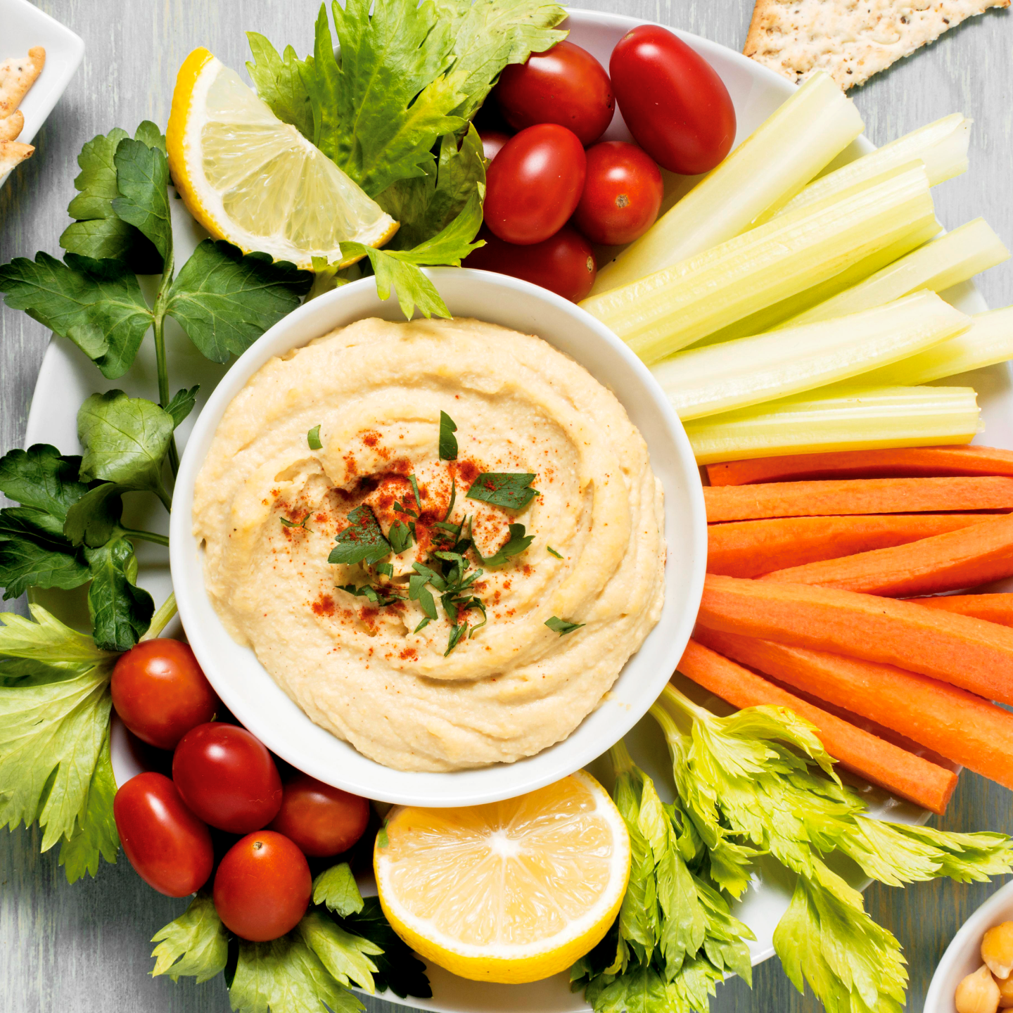 vegetable sticks on a round plate with a hummus dip