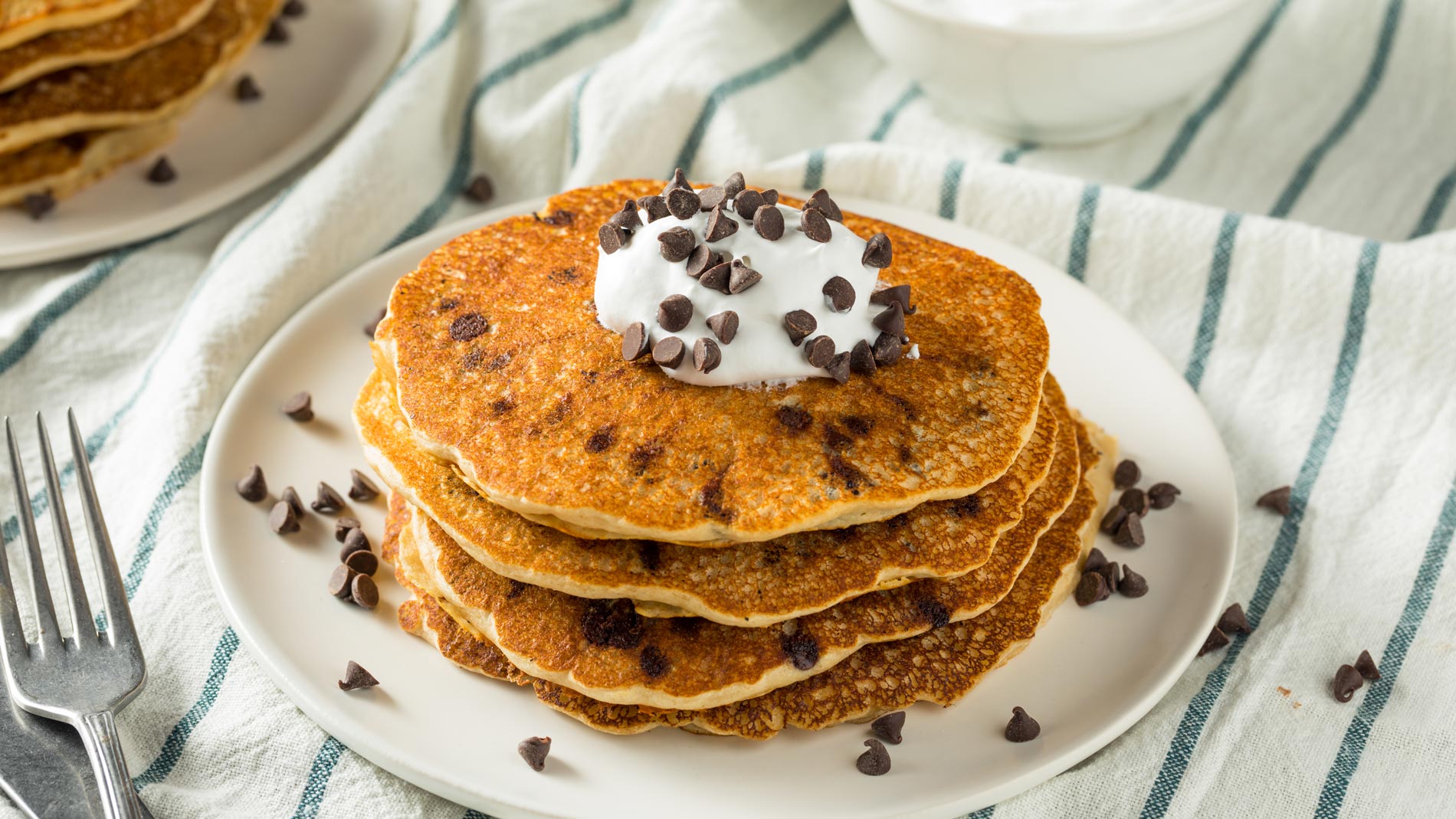 a pile of vegan pancakes with chocolate chips and whipped cream