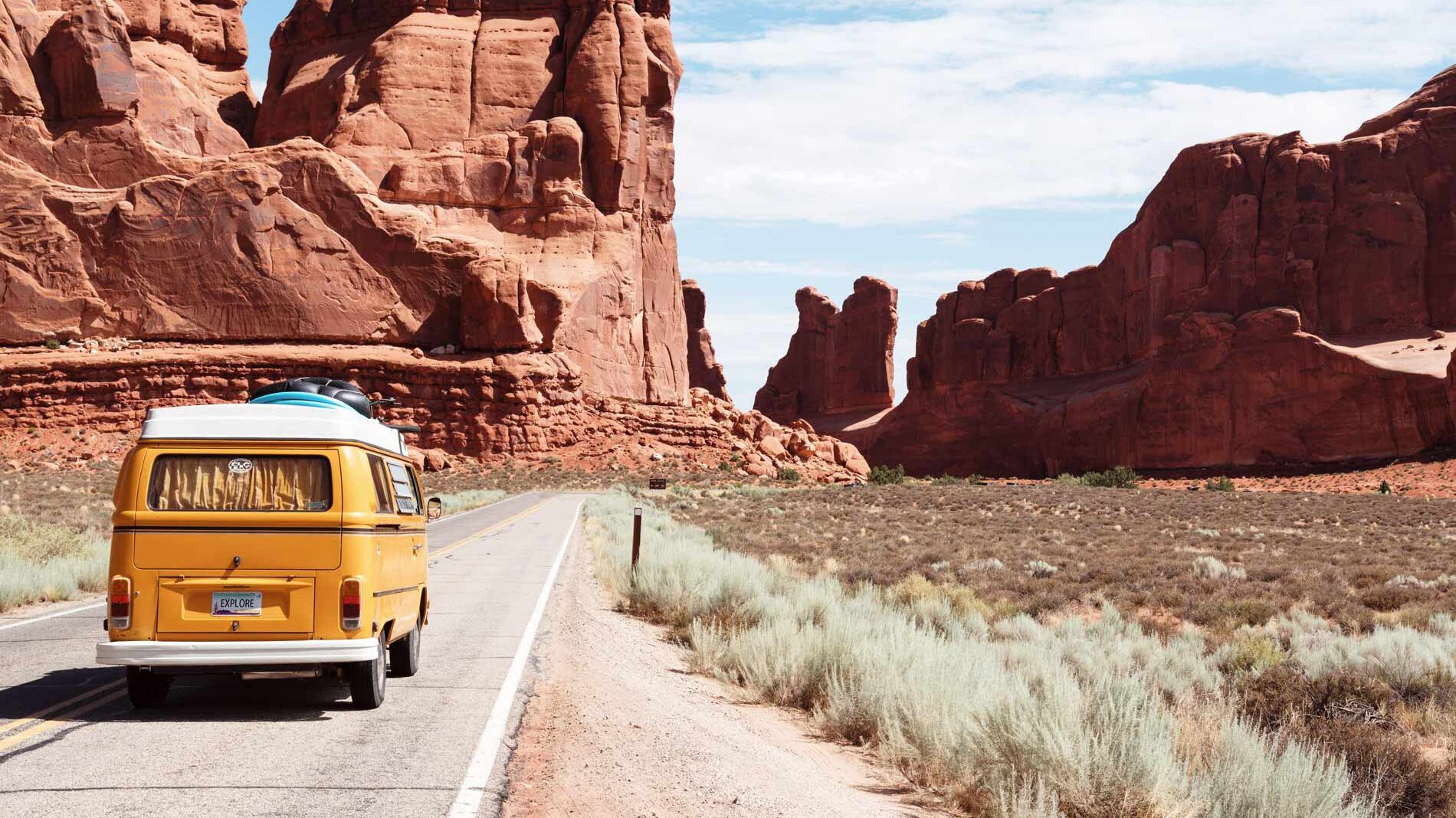 camper van driving on a road between mountains