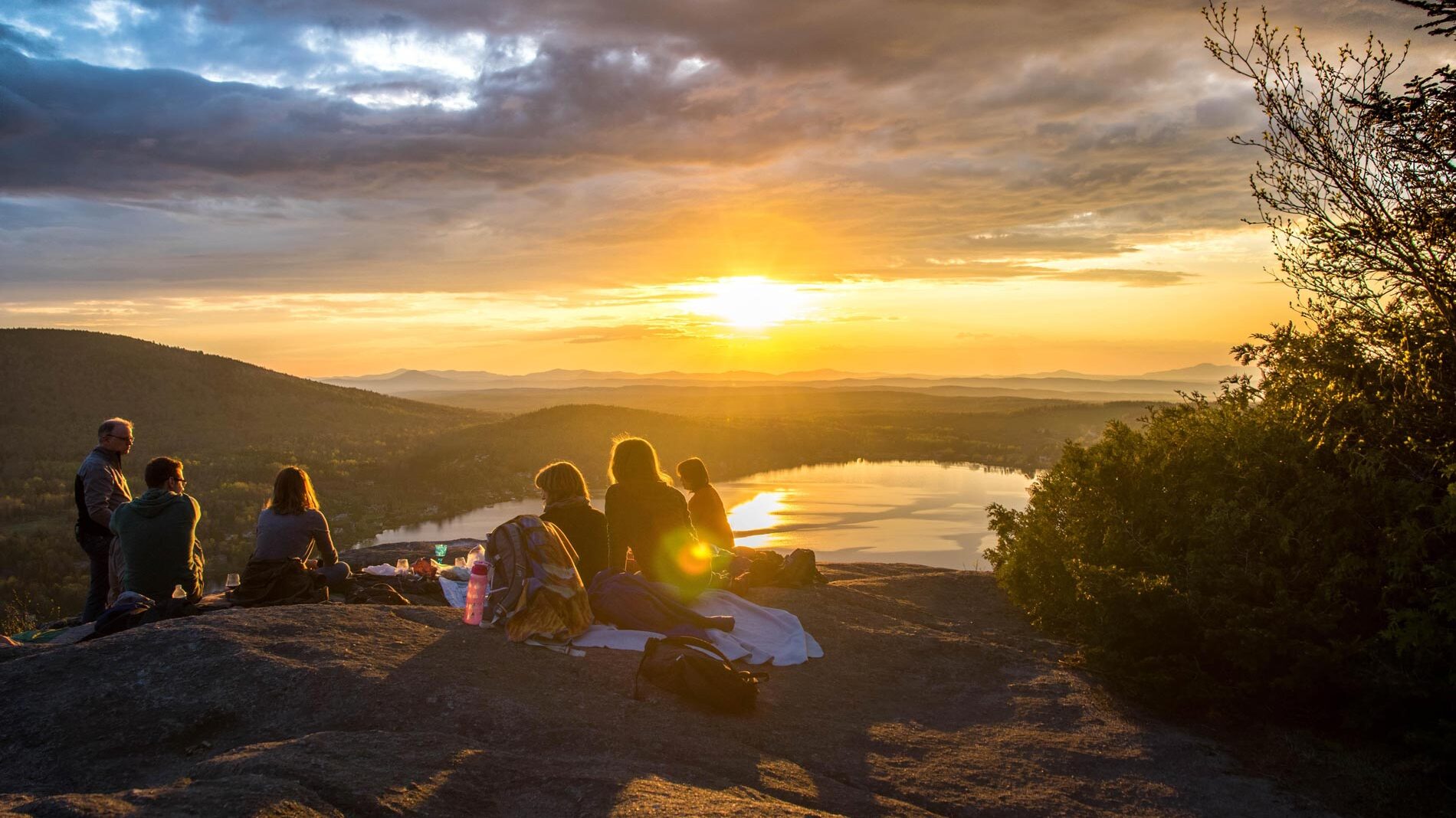 people camping on a mountain at sunset