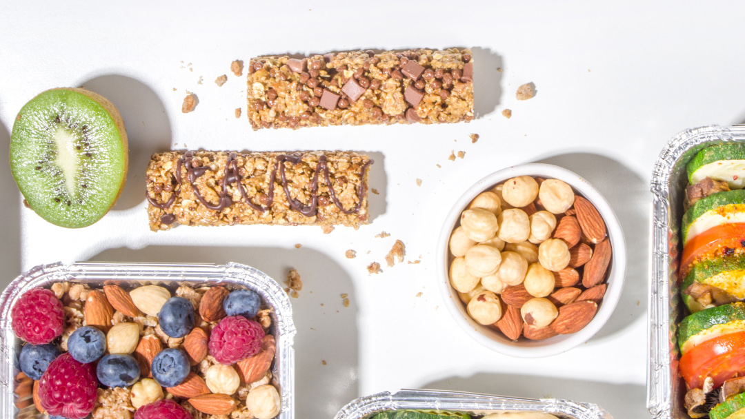 a spread of vegan snacks including fruits nuts and granola bars