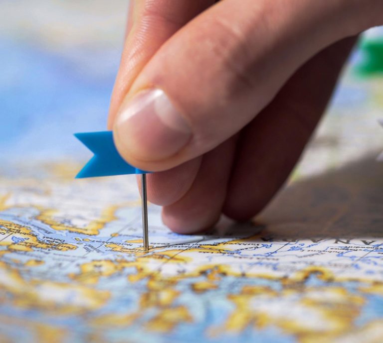 a hand pin pointing a pin to a map