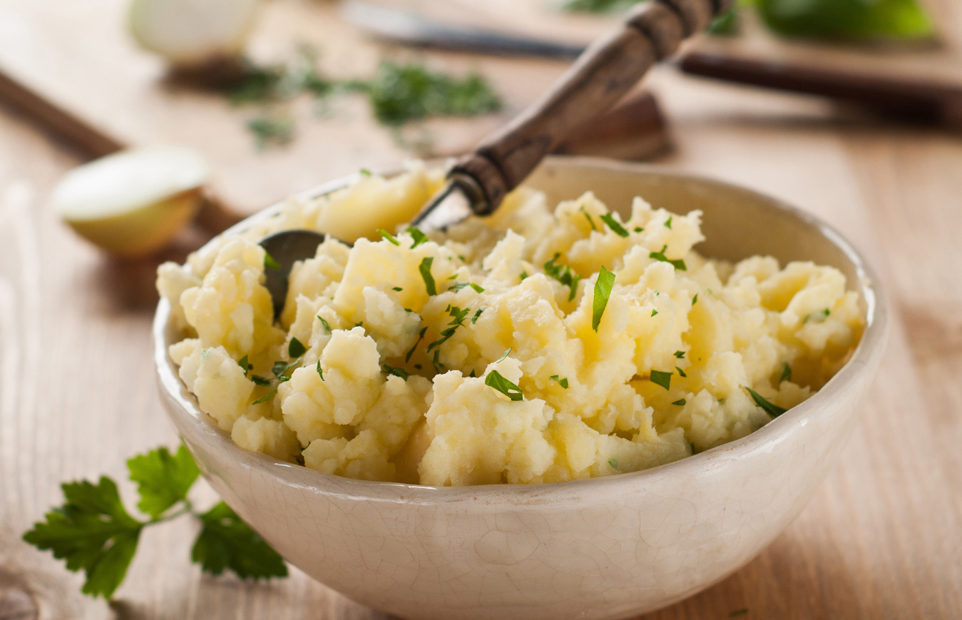 a bowl of mashed potatoes with parsley for garnish