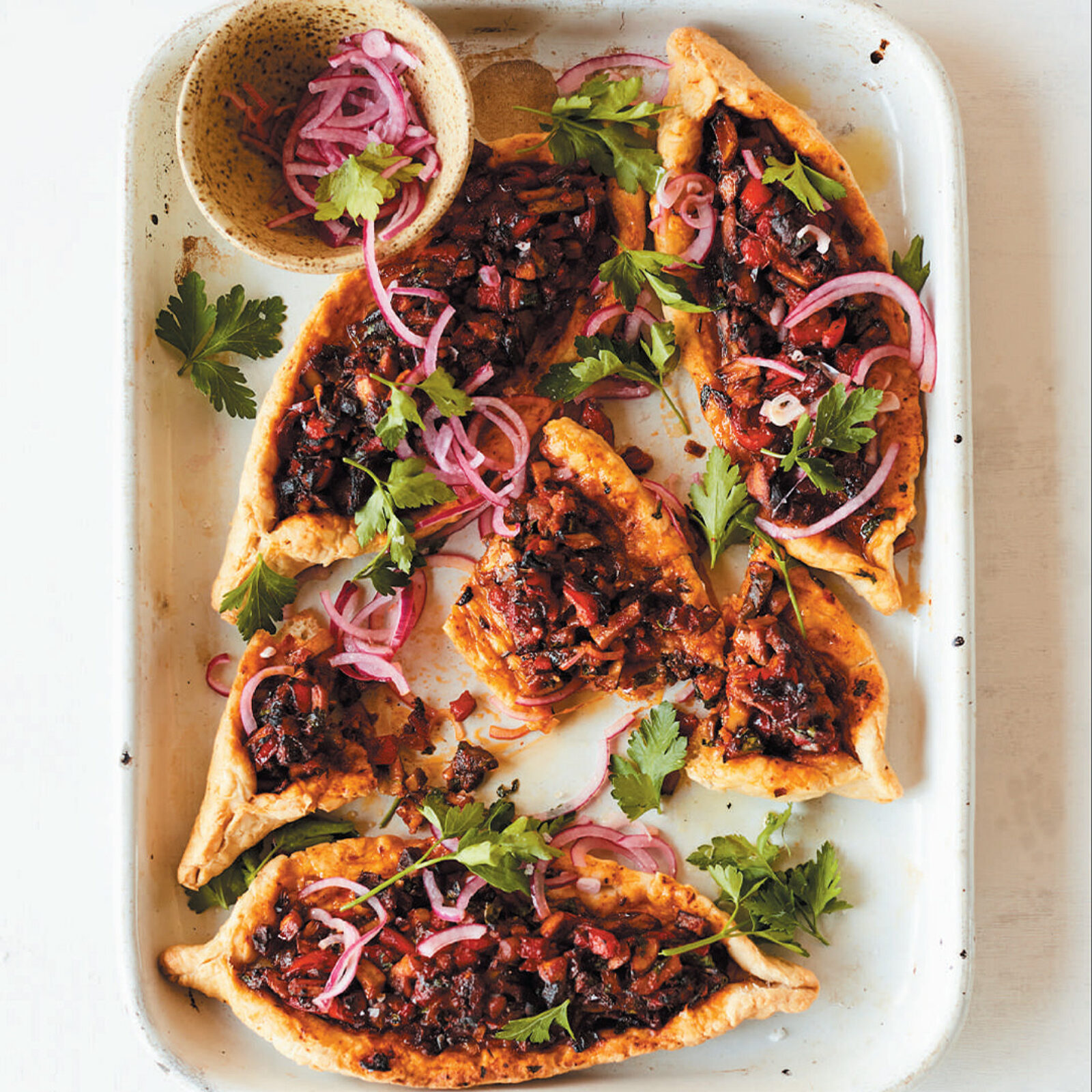 slices of baked pide with vegan meat filling in a pan