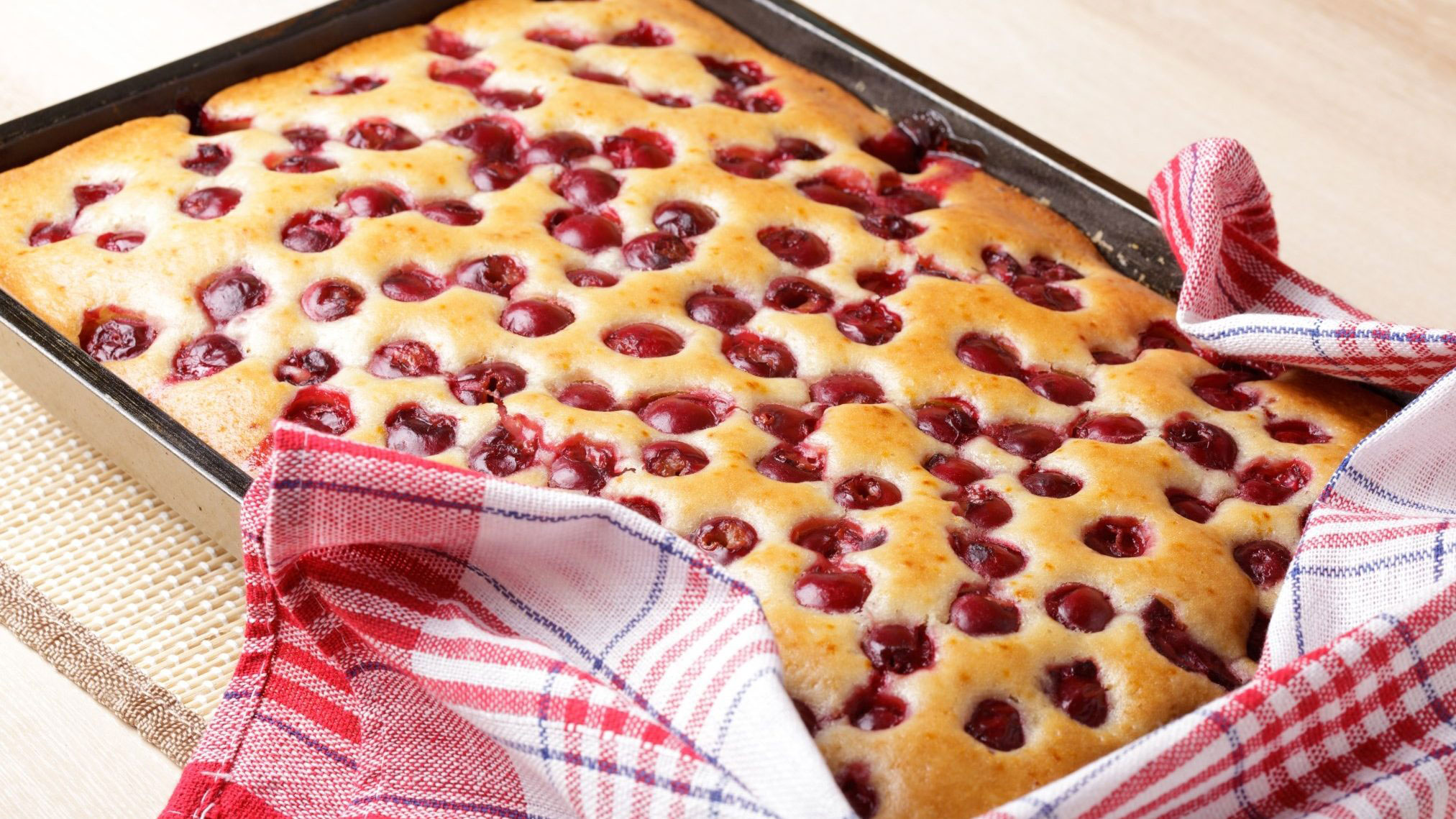 rectangle tray of fluffy sponge cake with lots of cherries in it