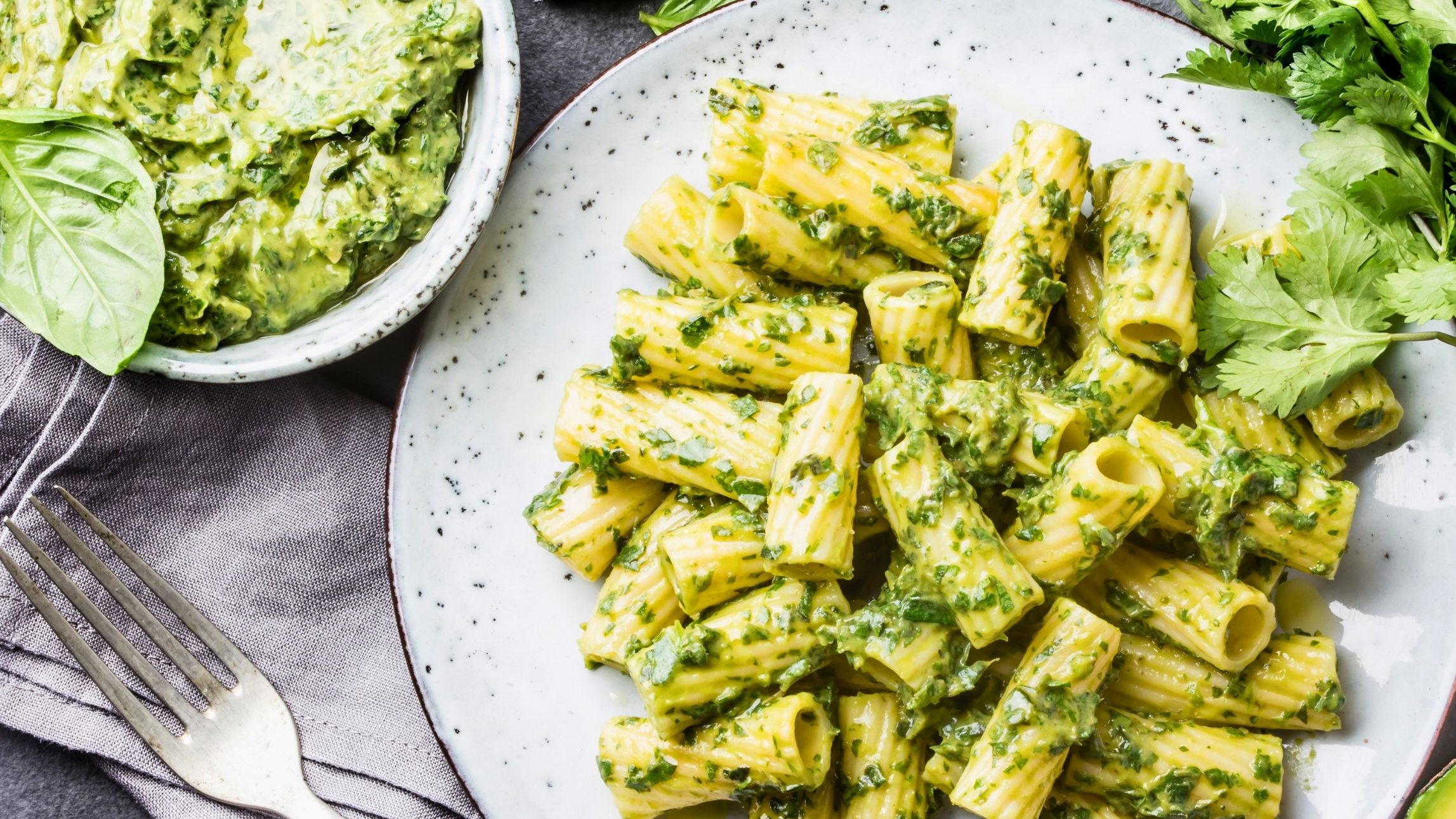 plate of rigatoni pasta in a creamy green sauce and chopped herbs