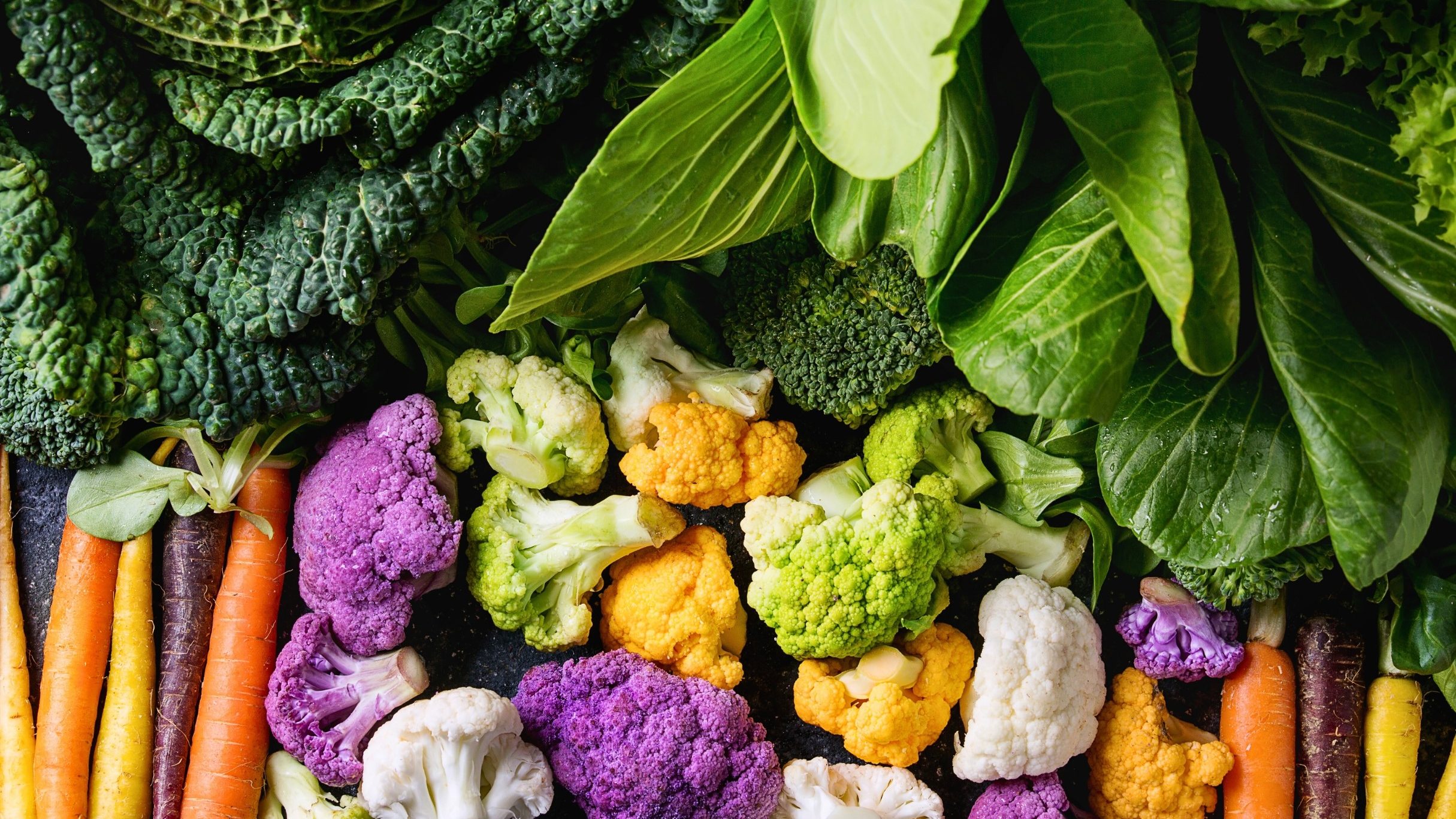 a variety of leafy green vegetables cauliflowers and carrots in different colors