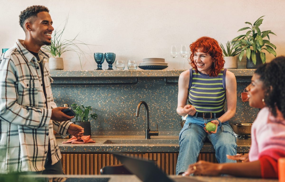 three friends sitting in a kitchen looking happy