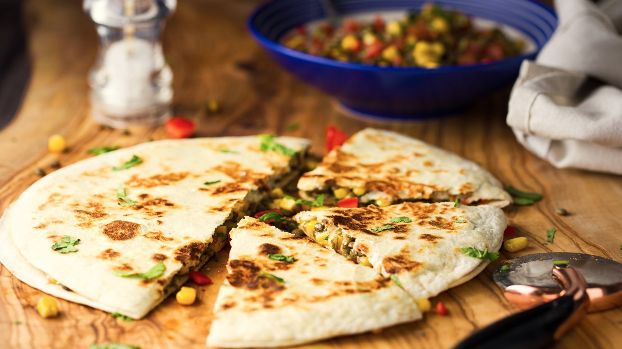 A quesadilla sliced and filled with chpped vegetables on a wooden table