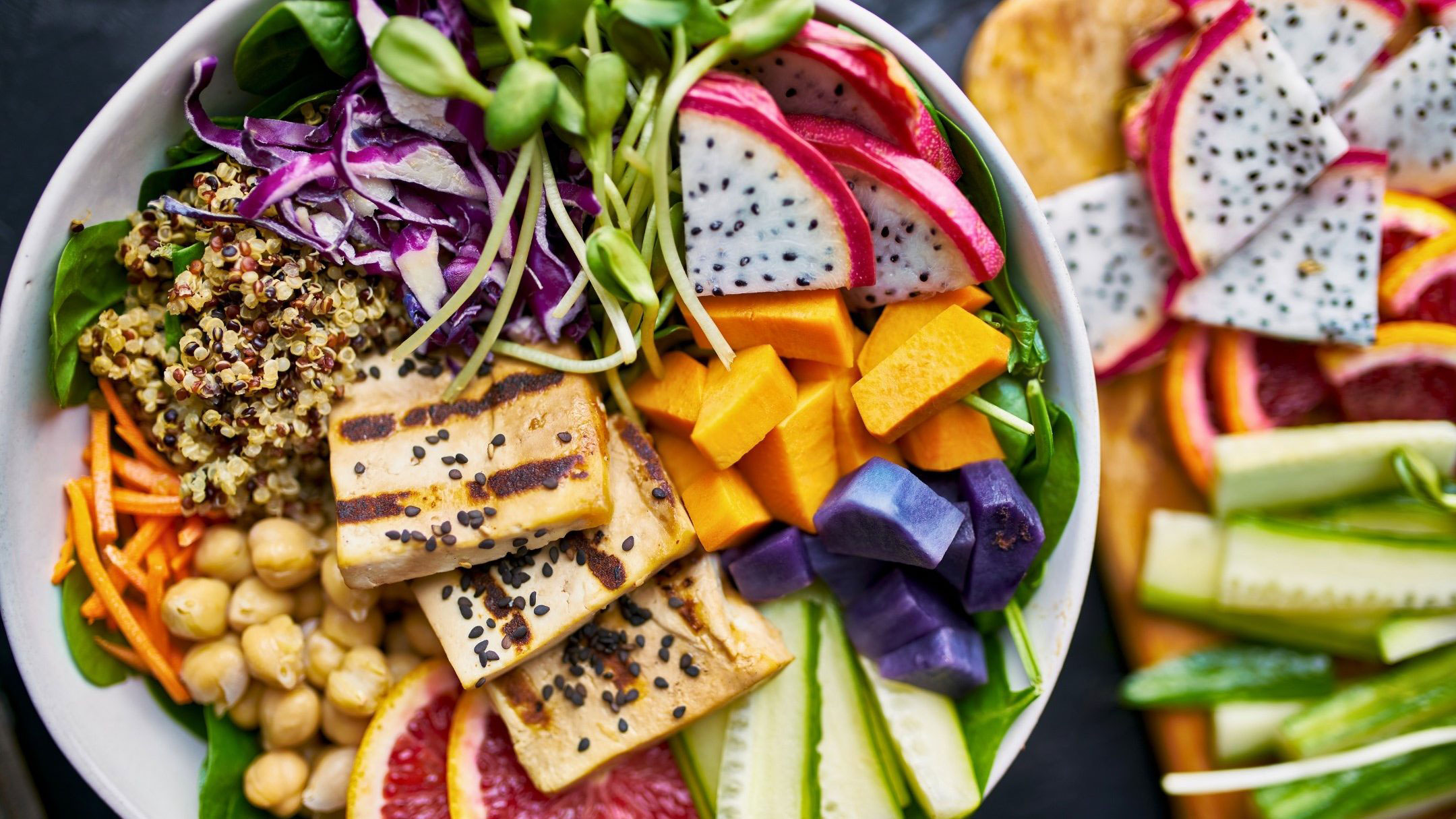 bowl full of colorful fresh vegetables and fruits, legumes, sprouts and grilled tofu slices