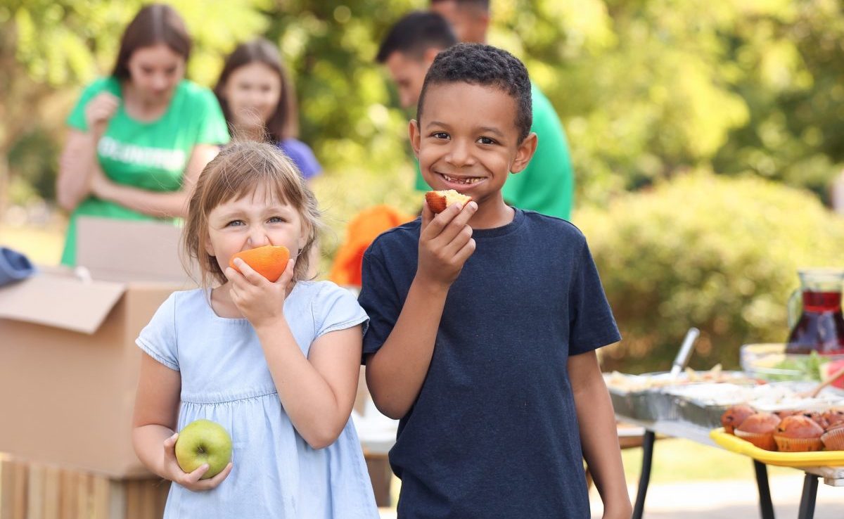 two kids eating fruits and smiling