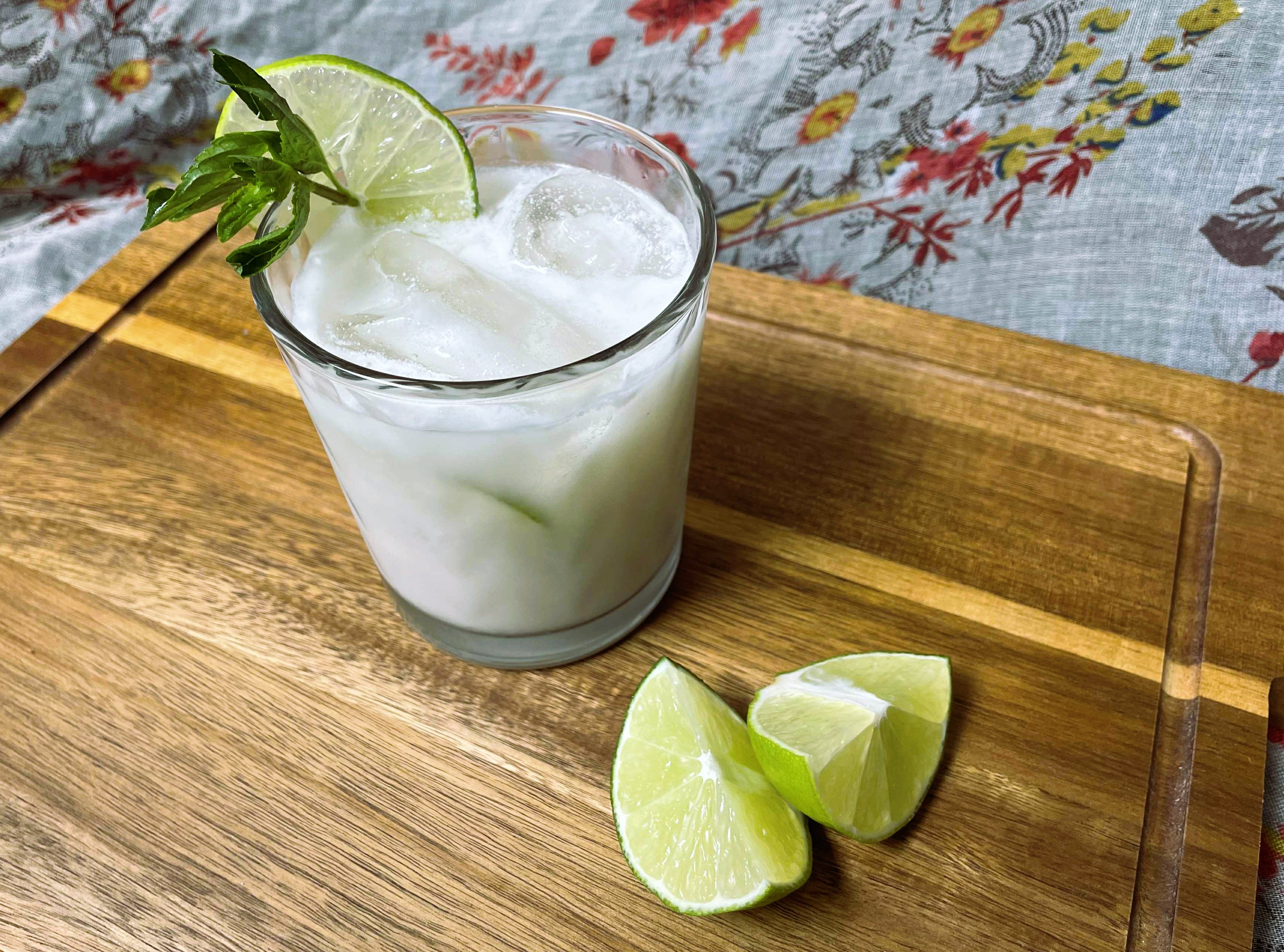 A glass of lemon coconut soda garnished with lime wedges